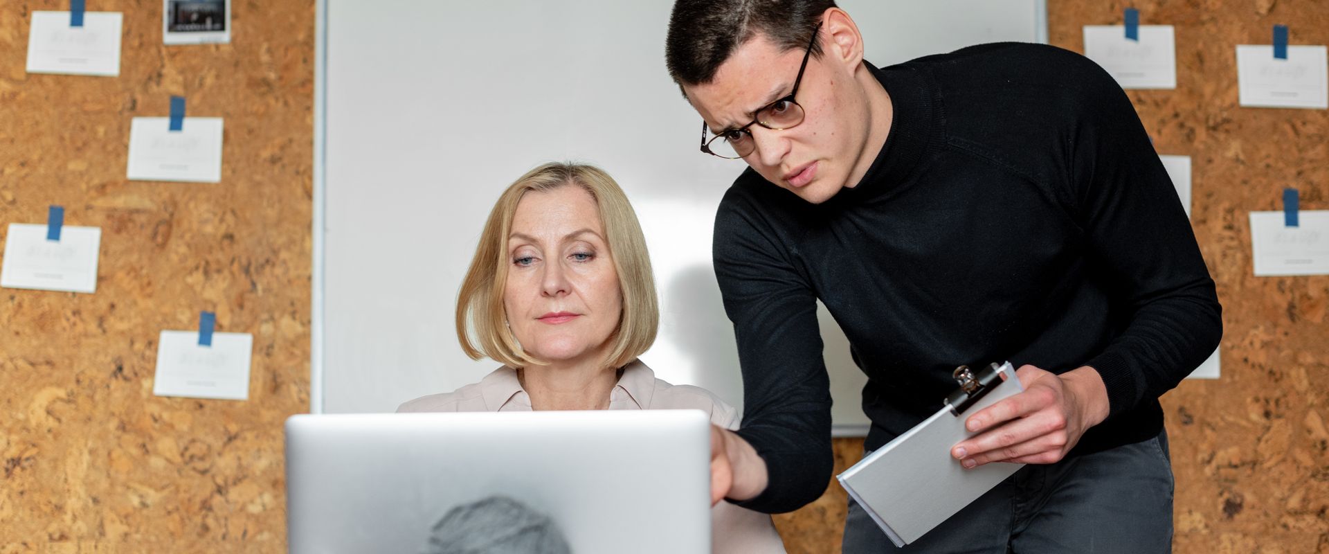 Zwei Personen arbeiten an einer Pinnwand mit Notizen